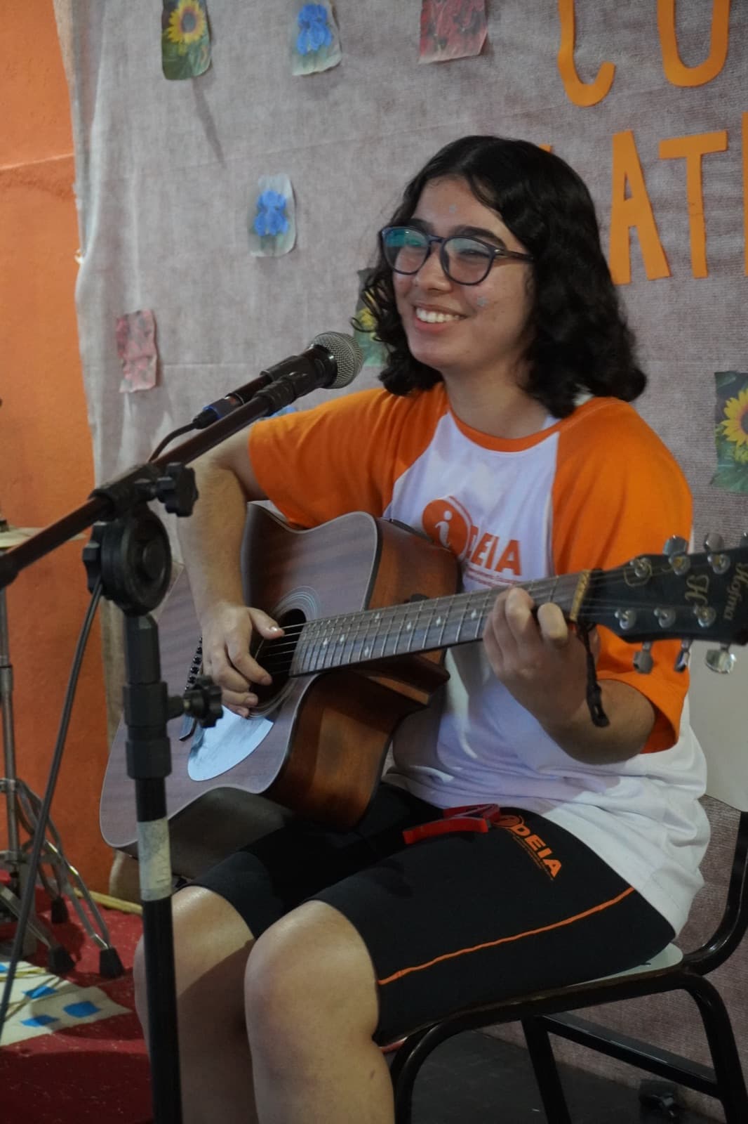 Aluna cantando e tocando violão no Sarau do IDEIA
