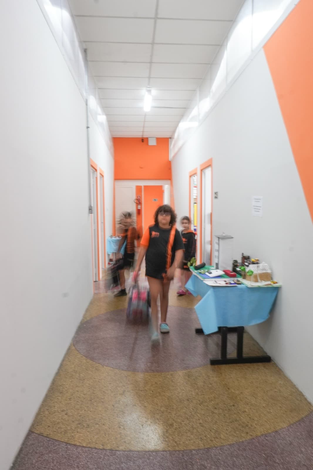 Corredor interno com paredes laranja e maquetes dos alunos