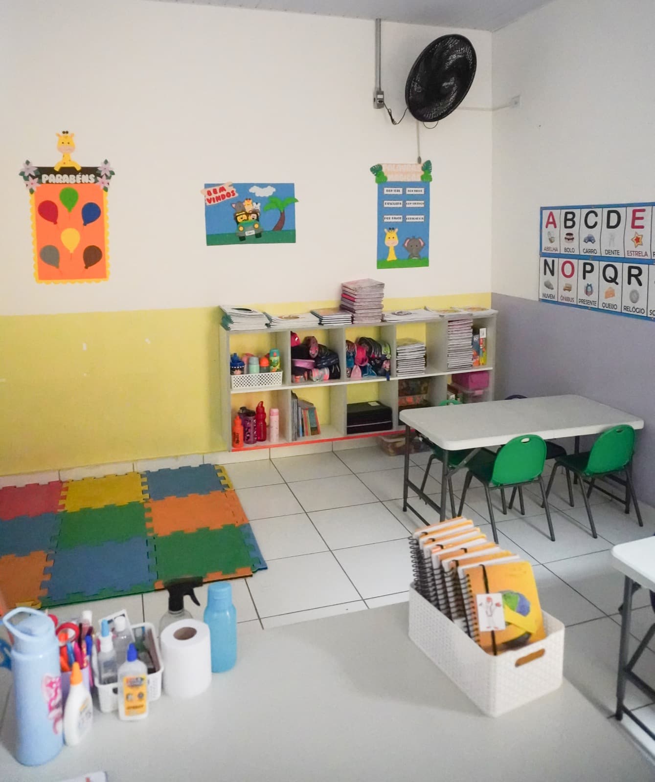 Sala da Educação Infantil com alfabeto, brinquedos e mesinhas verdes