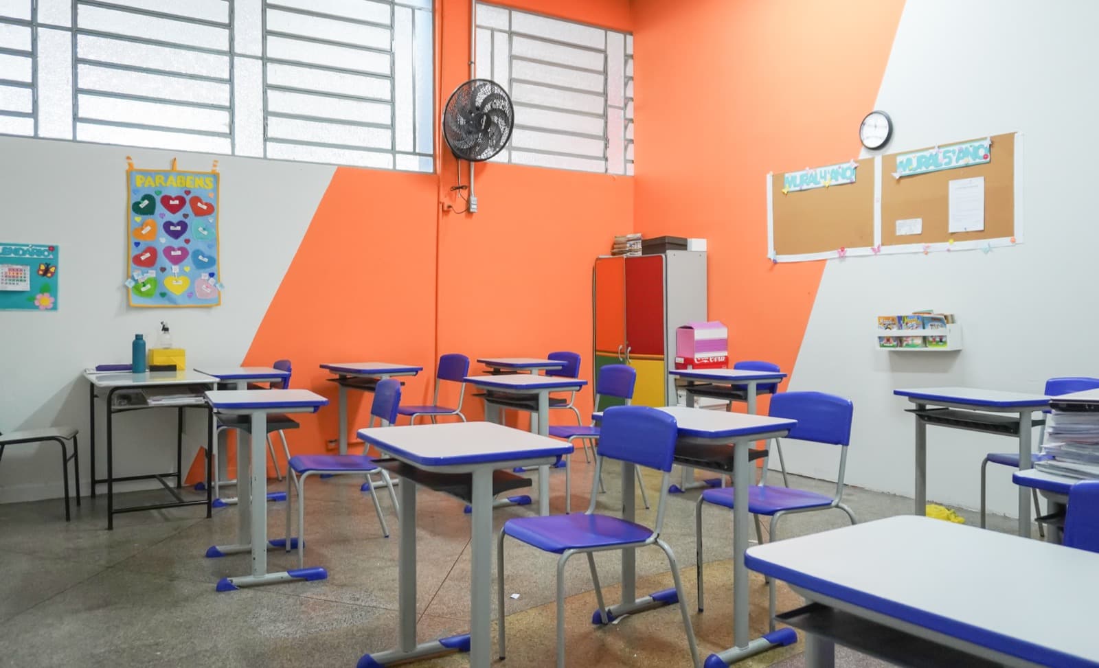 Sala do Fundamental I com mesas azuis e mural dos projetos