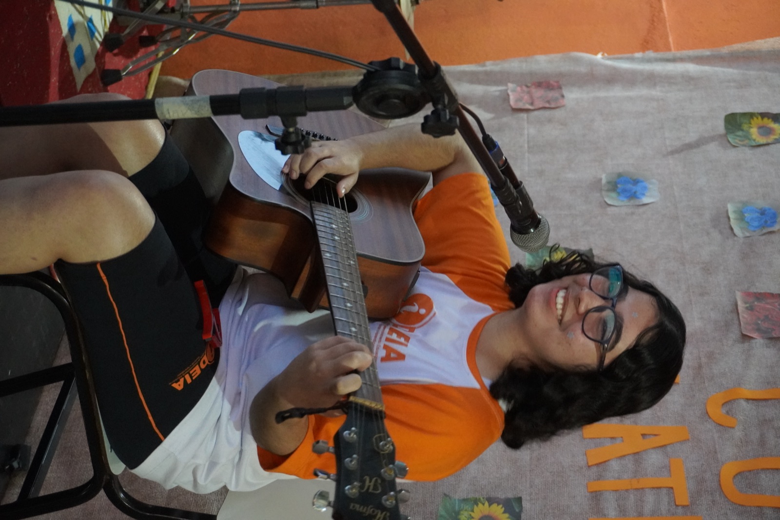 Aluna do IDEIA cantando e tocando violão no Sarau Cultural Latinidades